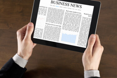 Businessman hands are holding the touch screen device with business news on screen